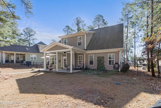 rear view of property with a patio, roof with shingles, a ceiling fan, and fence