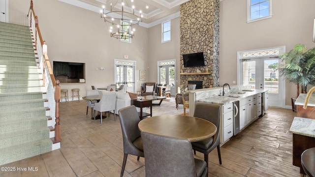 dining space with stairs, french doors, coffered ceiling, and a fireplace