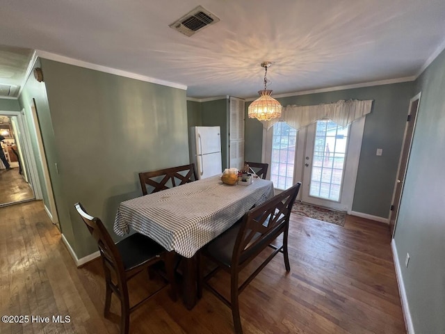 dining area featuring visible vents, baseboards, ornamental molding, wood finished floors, and a notable chandelier