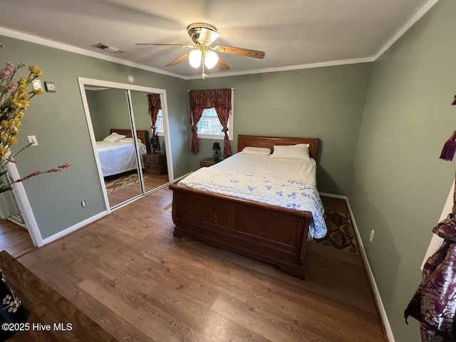 unfurnished bedroom featuring visible vents, baseboards, wood finished floors, and crown molding