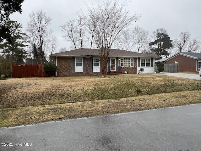 ranch-style home with brick siding, concrete driveway, and fence