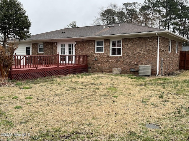 rear view of house with a deck, a lawn, brick siding, and french doors