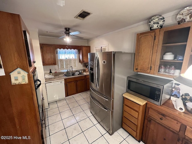 kitchen with visible vents, brown cabinets, a sink, backsplash, and stainless steel appliances