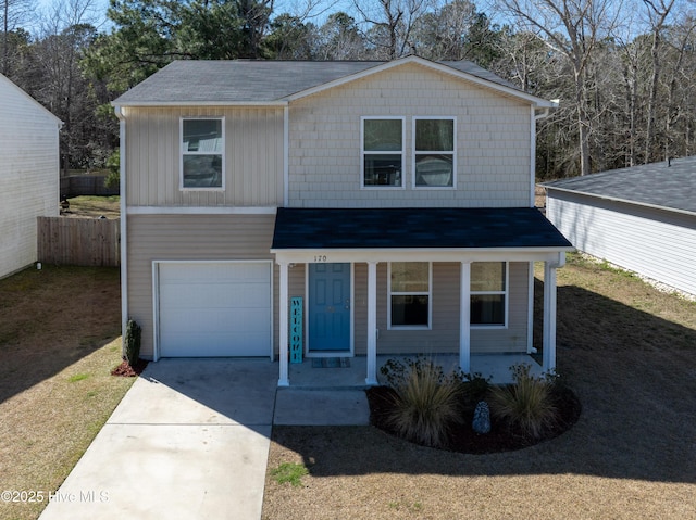 traditional-style house with concrete driveway, a porch, fence, and a front yard