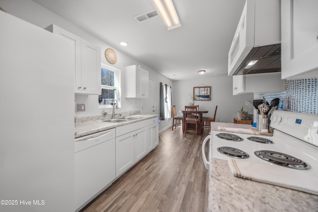 kitchen with light wood-style flooring, a sink, range hood, white appliances, and light countertops