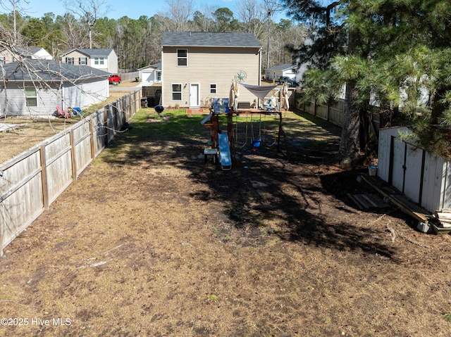 rear view of house featuring a fenced backyard, a storage unit, a playground, and an outdoor structure