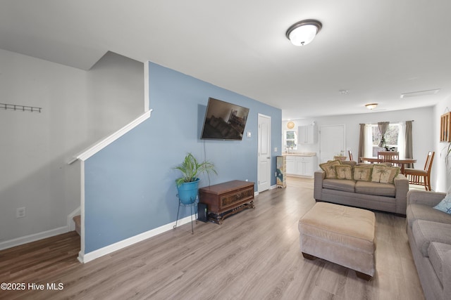 living area with stairs, baseboards, and wood finished floors