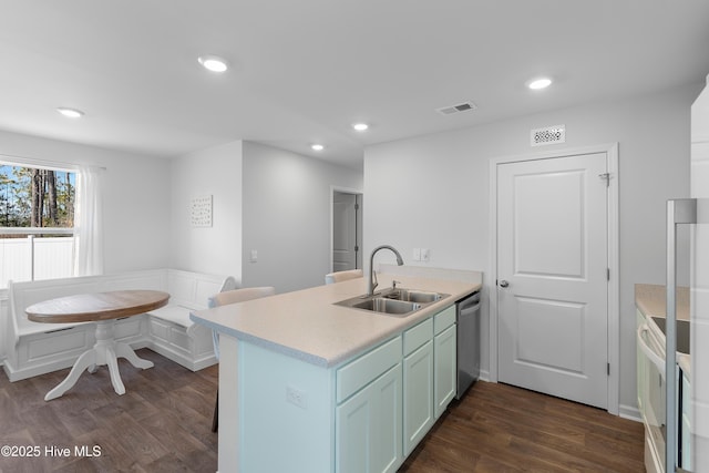 kitchen featuring visible vents, dark wood-type flooring, a sink, a peninsula, and dishwasher