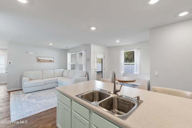 kitchen with a sink, open floor plan, dark wood finished floors, recessed lighting, and light countertops