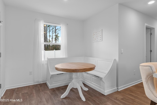 dining area featuring baseboards, breakfast area, recessed lighting, wood finished floors, and a decorative wall