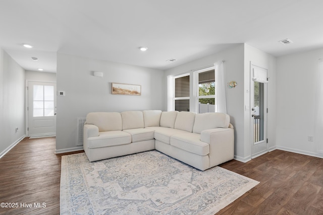 living area with dark wood finished floors, visible vents, and baseboards