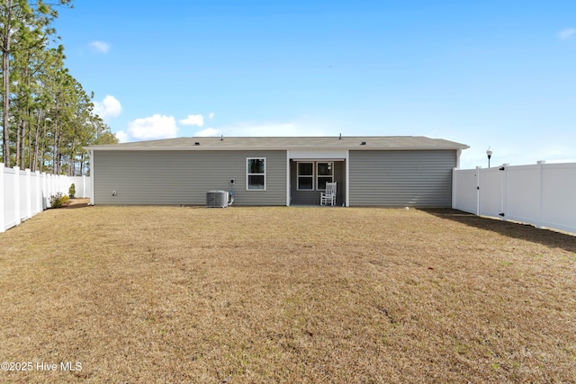 rear view of property with central air condition unit, a lawn, and a fenced backyard