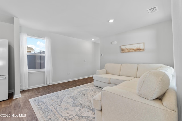 living area with recessed lighting, visible vents, baseboards, and wood finished floors