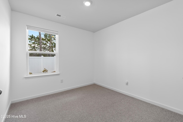 carpeted spare room with visible vents and baseboards