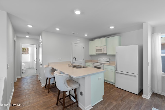 kitchen featuring a sink, a kitchen breakfast bar, white appliances, and dark wood-style flooring