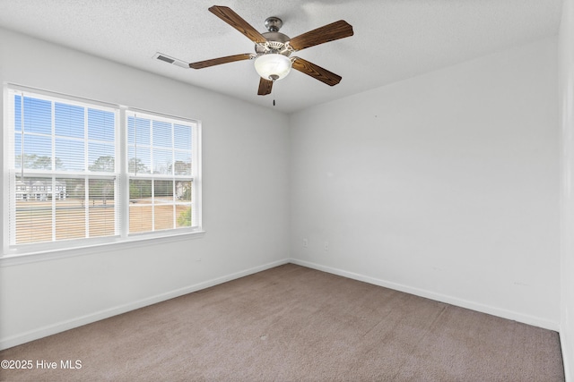 carpeted spare room with visible vents, a textured ceiling, baseboards, and a ceiling fan