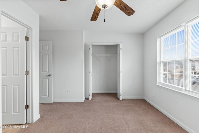 unfurnished bedroom featuring light carpet, a closet, baseboards, and a ceiling fan