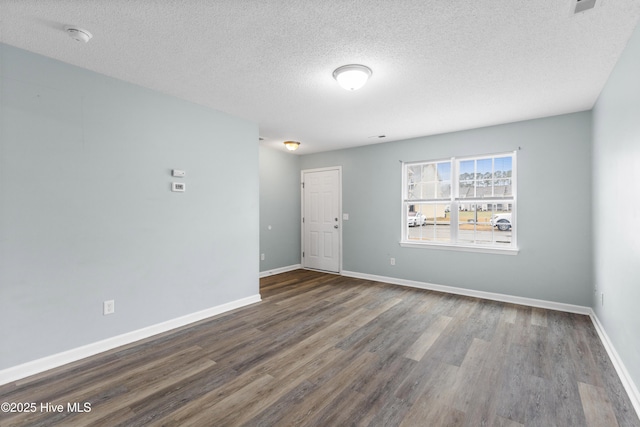 unfurnished room with a textured ceiling, baseboards, and wood finished floors