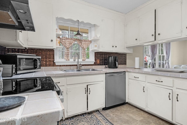 kitchen with a sink, dishwasher, tile countertops, and under cabinet range hood