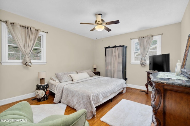 bedroom with visible vents, a ceiling fan, baseboards, and wood finished floors