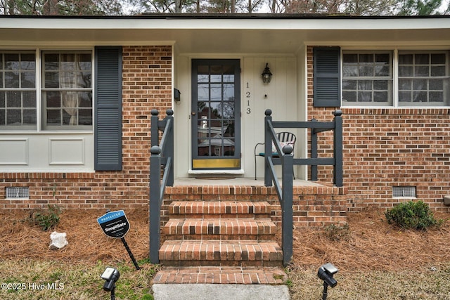 doorway to property featuring crawl space and brick siding