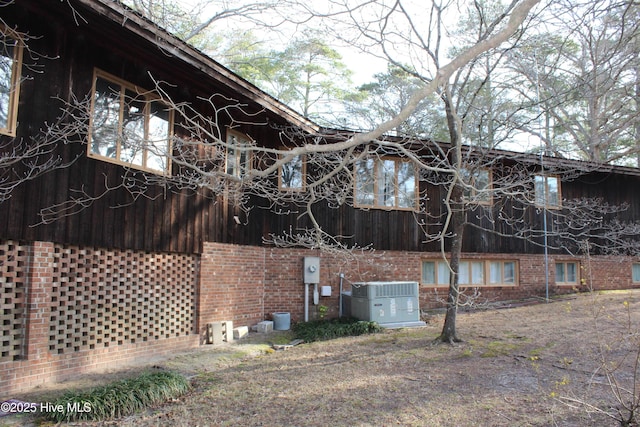 view of side of home featuring brick siding and central AC unit