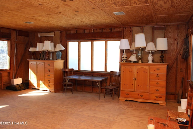 sitting room featuring wooden walls, wooden ceiling, a wall mounted AC, and visible vents