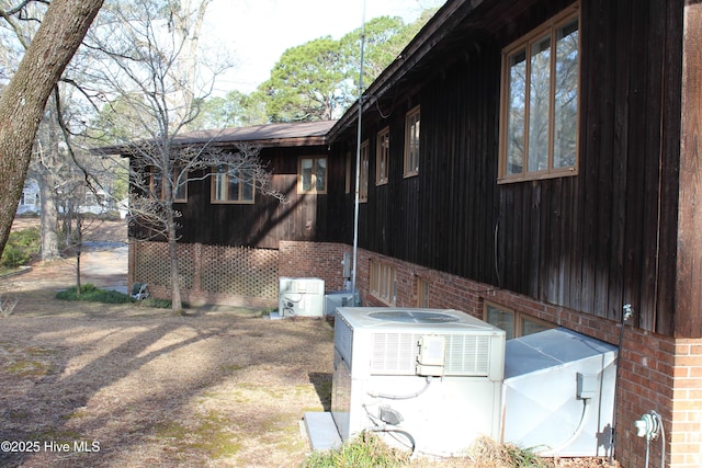 view of side of property with central air condition unit and brick siding