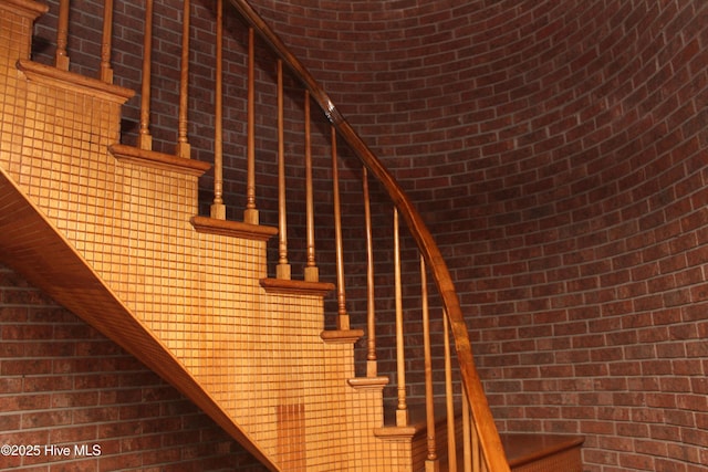 staircase featuring brick wall