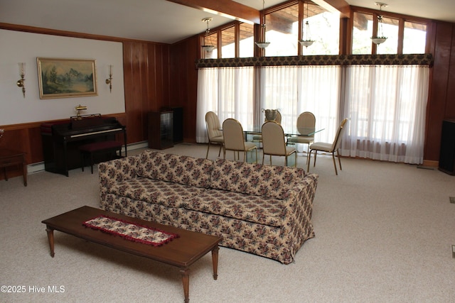 living room featuring lofted ceiling with beams, carpet flooring, baseboard heating, and wooden walls