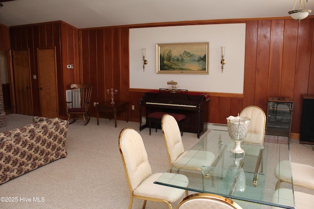 carpeted dining space featuring wooden walls and a baseboard radiator