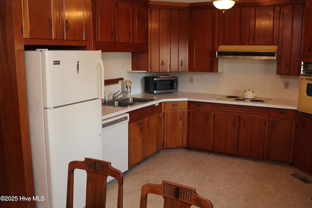 kitchen featuring visible vents, under cabinet range hood, a sink, white appliances, and light countertops