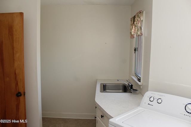 clothes washing area featuring a sink, baseboards, washer / clothes dryer, and cabinet space