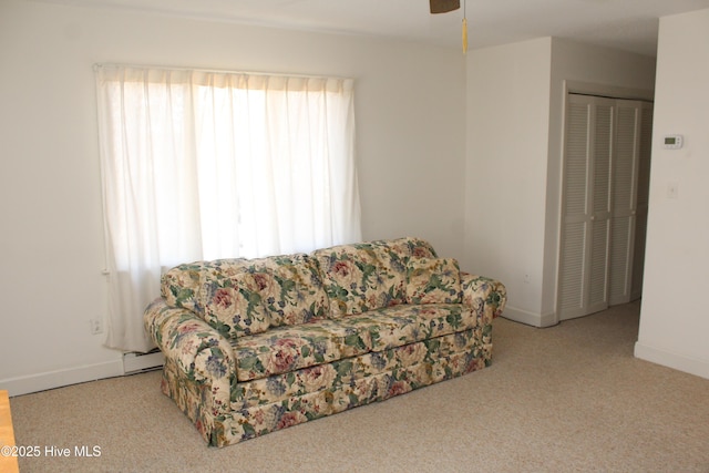 living room with a baseboard heating unit, baseboards, carpet, and a ceiling fan