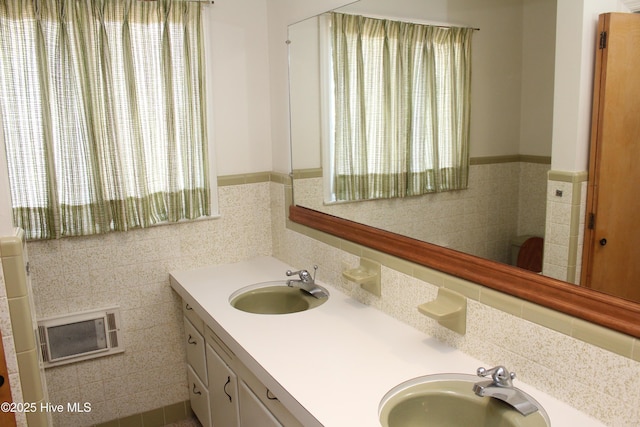 bathroom with tile walls, double vanity, wainscoting, and a sink