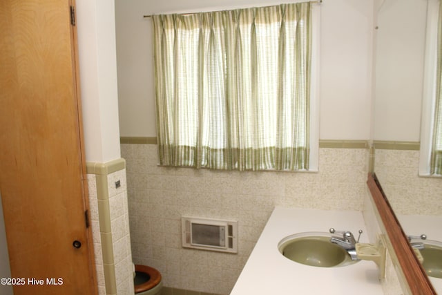 bathroom featuring toilet, tile walls, and a sink