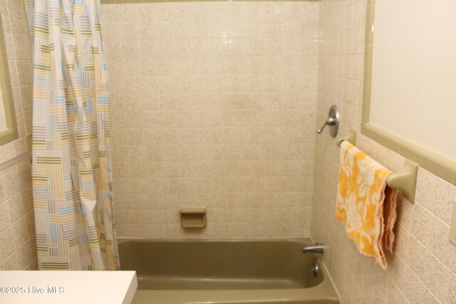 full bath with shower / bathtub combination with curtain and tile walls