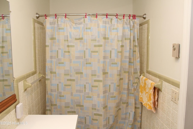 bathroom featuring a shower with shower curtain and tile walls