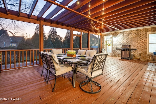 deck at dusk with outdoor dining space and a grill