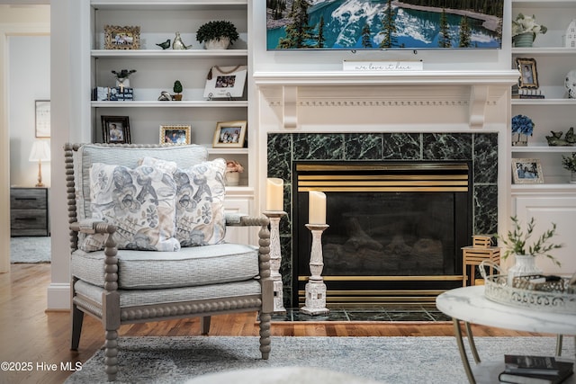 sitting room featuring a high end fireplace, built in shelves, and wood finished floors