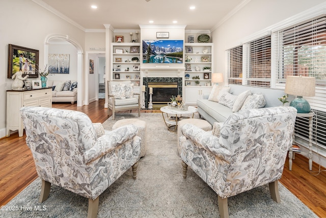 living room featuring a fireplace, crown molding, recessed lighting, and light wood-style floors