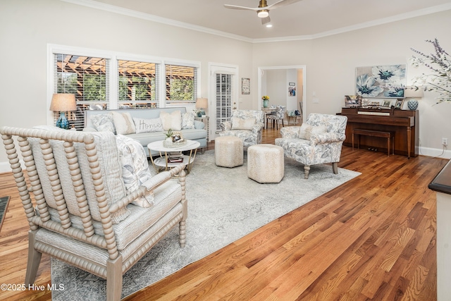 living room featuring baseboards, a ceiling fan, wood finished floors, and crown molding