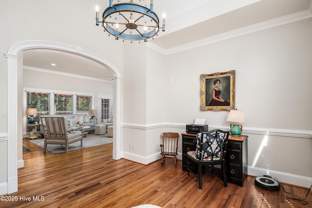 office space featuring crown molding, baseboards, a high ceiling, wood finished floors, and a notable chandelier