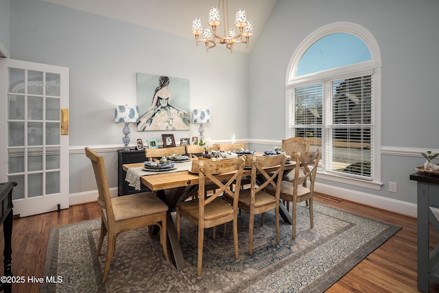 dining room featuring visible vents, baseboards, a chandelier, lofted ceiling, and wood finished floors