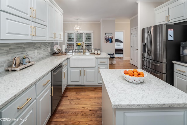 kitchen with dark wood-type flooring, a sink, backsplash, appliances with stainless steel finishes, and crown molding