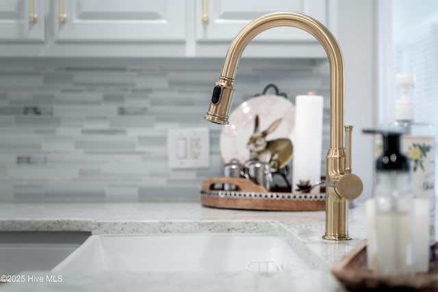 room details with a sink, light stone counters, and white cabinetry