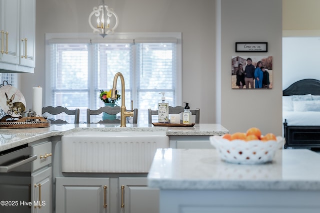 kitchen with a wealth of natural light, dishwashing machine, an inviting chandelier, and a sink