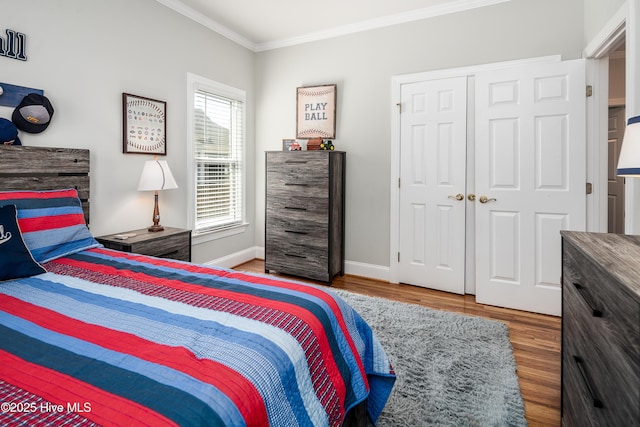 bedroom with crown molding, wood finished floors, baseboards, and a closet