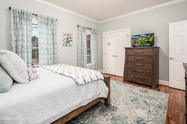 bedroom featuring a closet, baseboards, wood finished floors, and crown molding