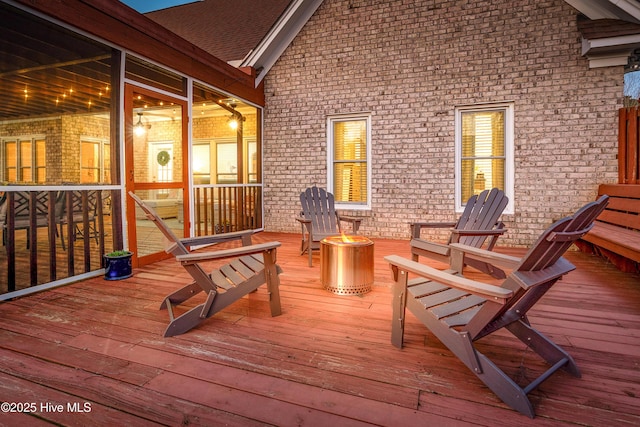 wooden deck featuring a sunroom and an outdoor fire pit